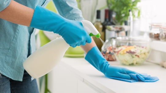 person with gloves and spray bottle cleaning